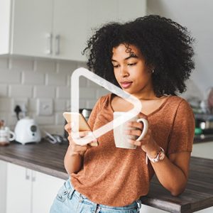 woman holding coffee mug and looking at cell phone