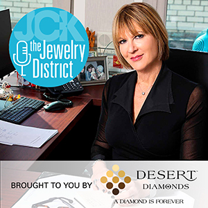 Rebecca Foerster of Hearts On Fire smiling with The Jewelry District and sponsor logos